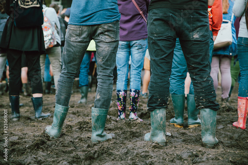 Closeup of muddy wellingtons. People attending on a rainy day at a music festival. 