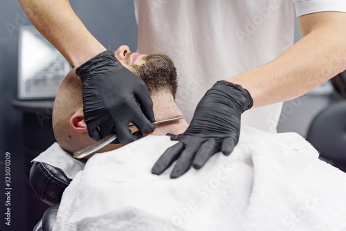 beard modeling in Barber shop, beard care for men, male beauty and care concept, shaving with a straight razor