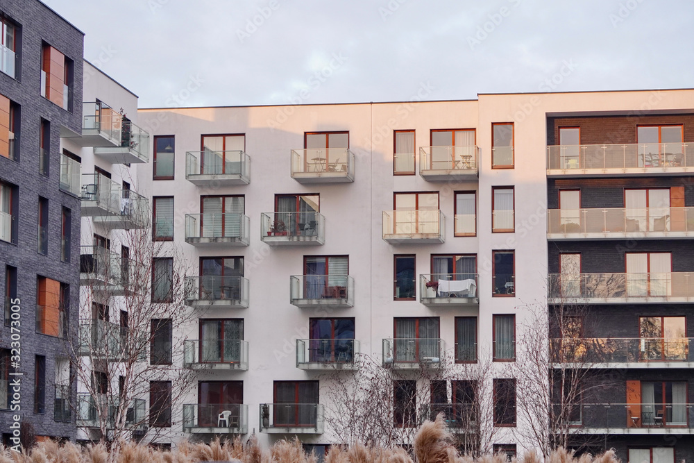 Parts of modern residential complexes in a European city in the sunset or dawn sun. Open balconies with glass railings, reflections and shadows, the play of light