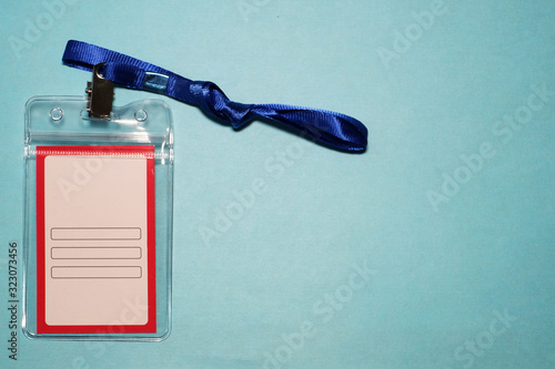 close-up plastic case of neck label hanging isolated on blue background, blank name-tag label