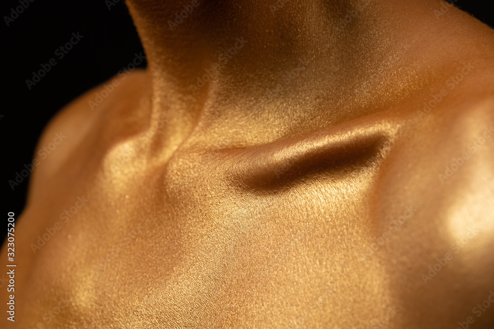 in gold paint a man. Shiny clavicle detail photo. Shiny body art