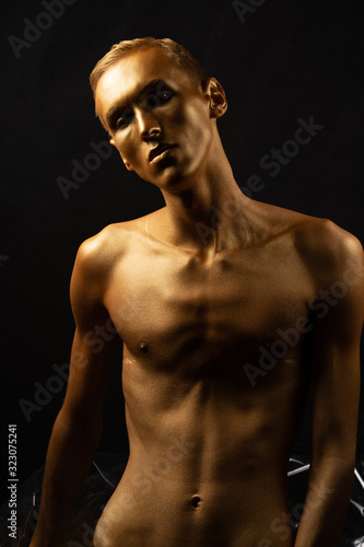 man in gold paint Shiny body art paint gold on a black background.