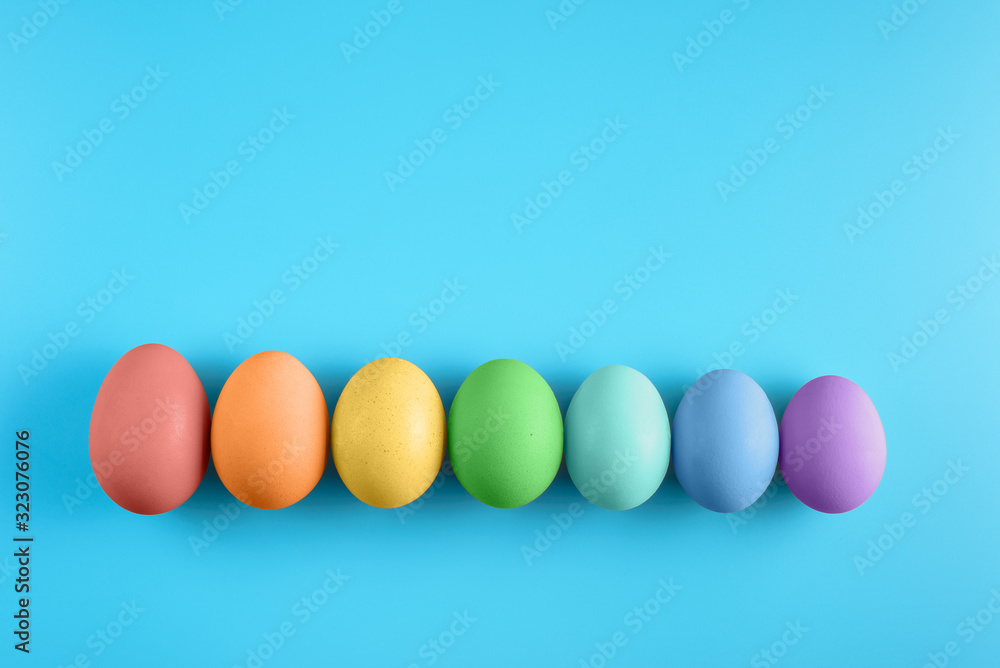Top view of seven bright painted easter eggs on blue surface. Colorful easter eggs decoration. Flat lay, top view. with copy space for text Top view of seven bright painted easter eggs on blue surface. Colorful easter eggs decoration. Flat lay, top view. with copy space for text