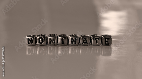 Nominate -  word from metal blocks - concept sepia tone photo on shine background