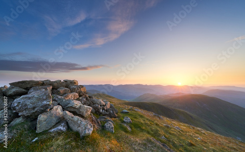 A bright sunset sky over the mountains of the Lake District from the summit og Ramspgill Head with views of The Knott and Rest Dodd below. © Duncan Andison