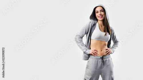 Studio photo of attractive positive young sporty woman with long hair in hood looking positively photo