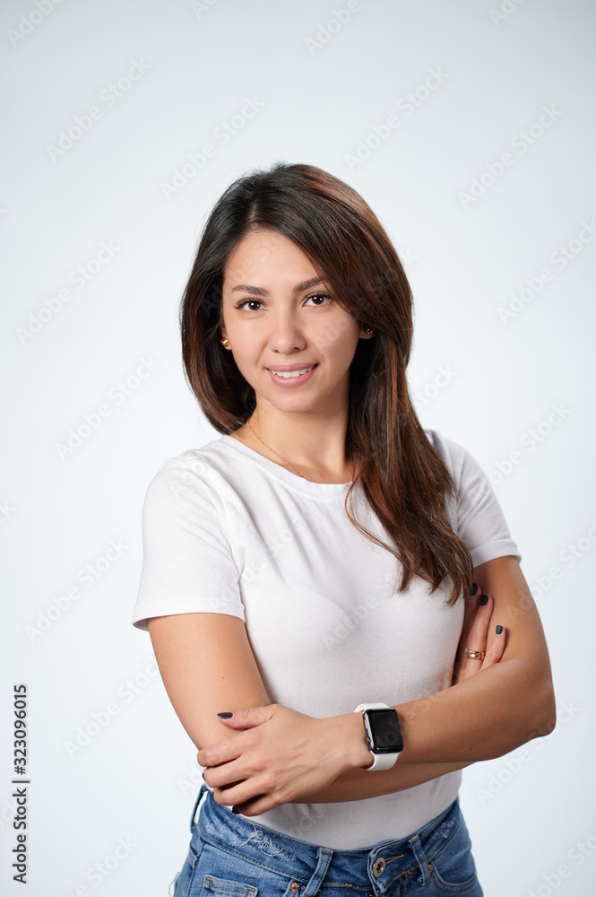 Smiling woman in white T-short standing with arms crossed, white bachground Smiling woman in white T-short standing with arms crossed, white bachground