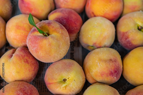 Close up full frame shot of beautiful peaches on sale at the local food market. Typical soft and hairy bright yellow and orange peel. Inviting.
