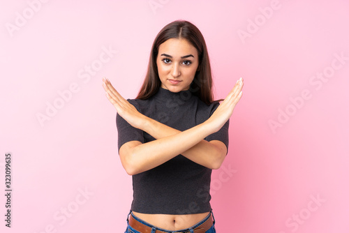 Young girl over isolated pink background making NO gesture