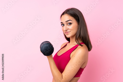 Young sport girl over isolated pink background making weightlifting
