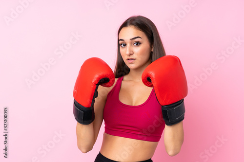 Young sport girl over isolated pink background with boxing gloves © luismolinero