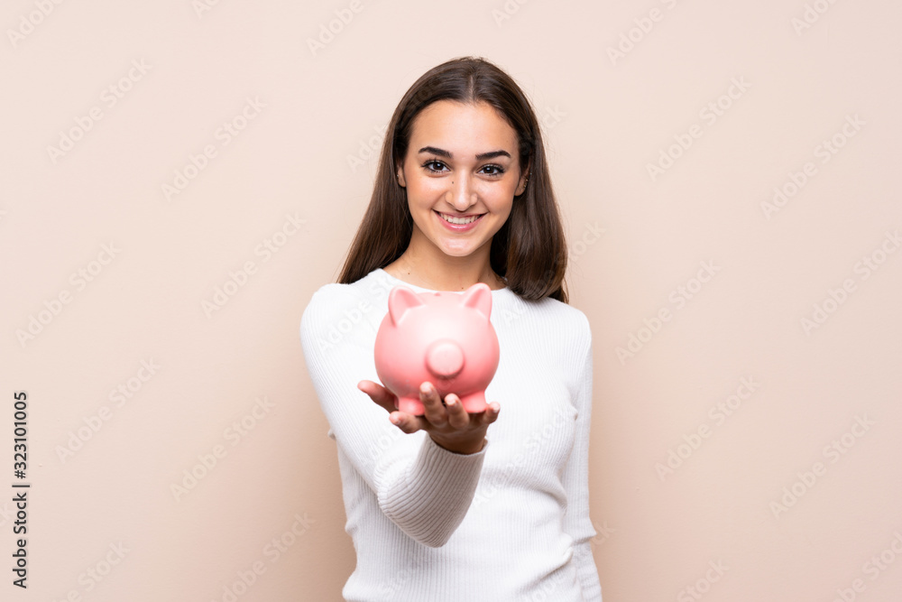 Young woman over isolated background holding a big piggybank Young woman over isolated background holding a big piggybank