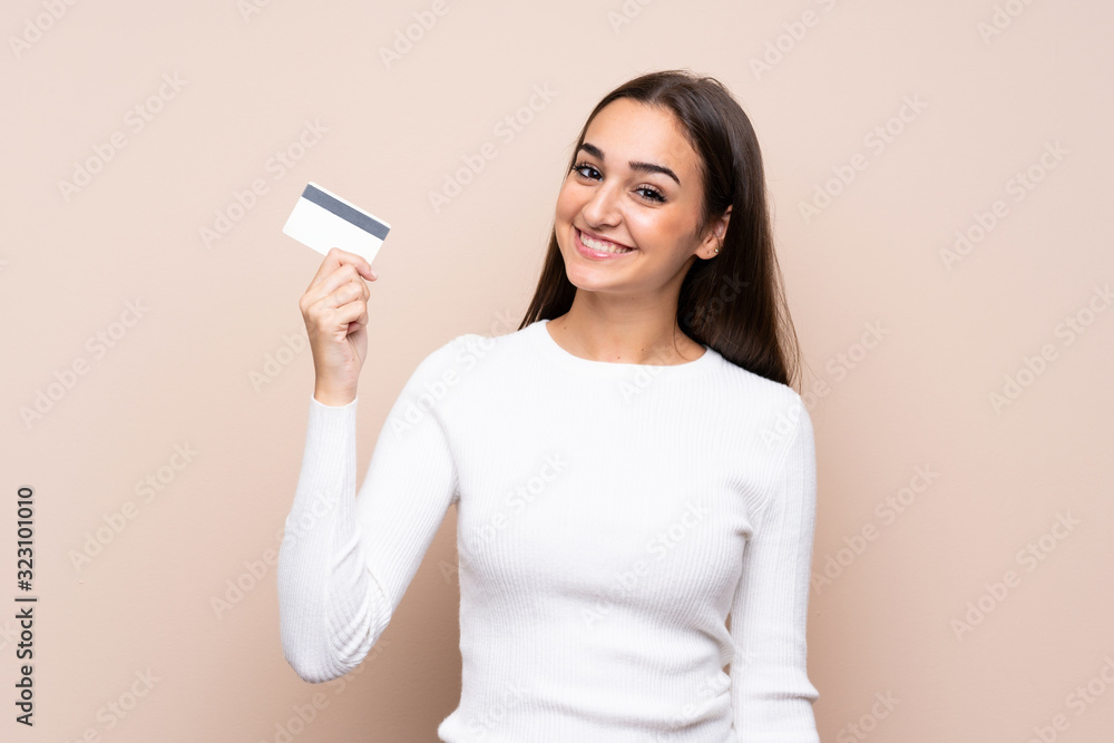 Young woman over isolated background holding a credit card Young woman over isolated background holding a credit card