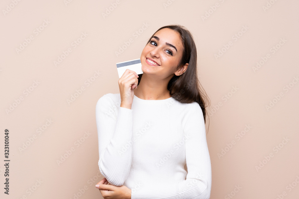 Young woman over isolated background holding a credit card Young woman over isolated background holding a credit card