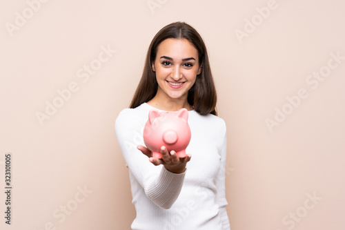 Young woman over isolated background holding a big piggybank © luismolinero