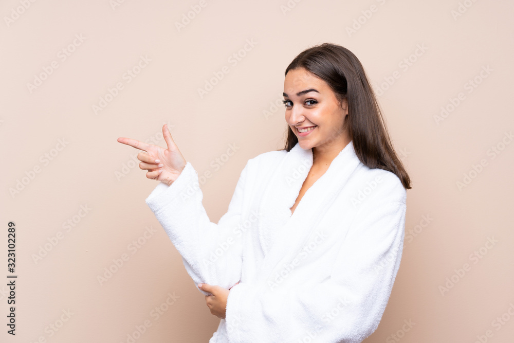 Young girl in a bathrobe over isolated background pointing finger to the side