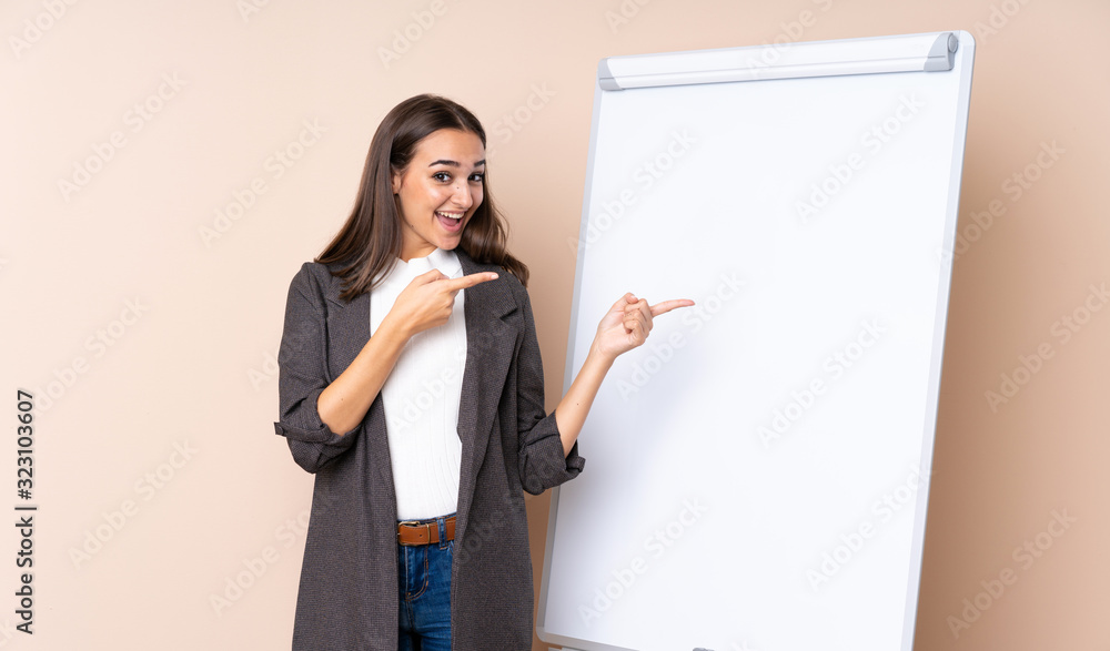 Young woman giving a presentation on white board surprised and pointing side Young woman giving a presentation on white board surprised and pointing side