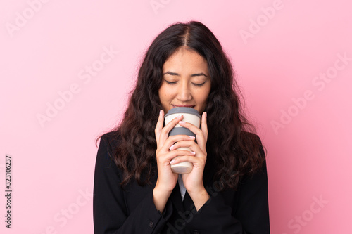 Mixed race business woman holding coffee to take away over isolated pink background