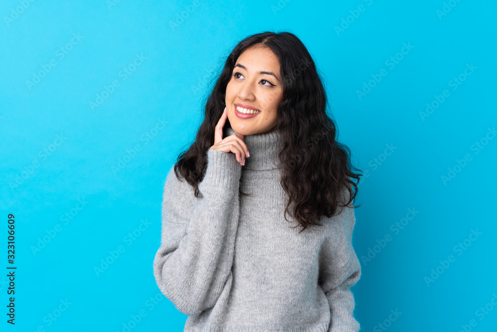 Spanish Chinese woman over isolated blue background thinking an idea while looking up Spanish Chinese woman over isolated blue background thinking an idea while looking up