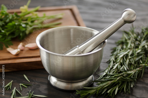 Photo metal mortar pestle on counter with herbs