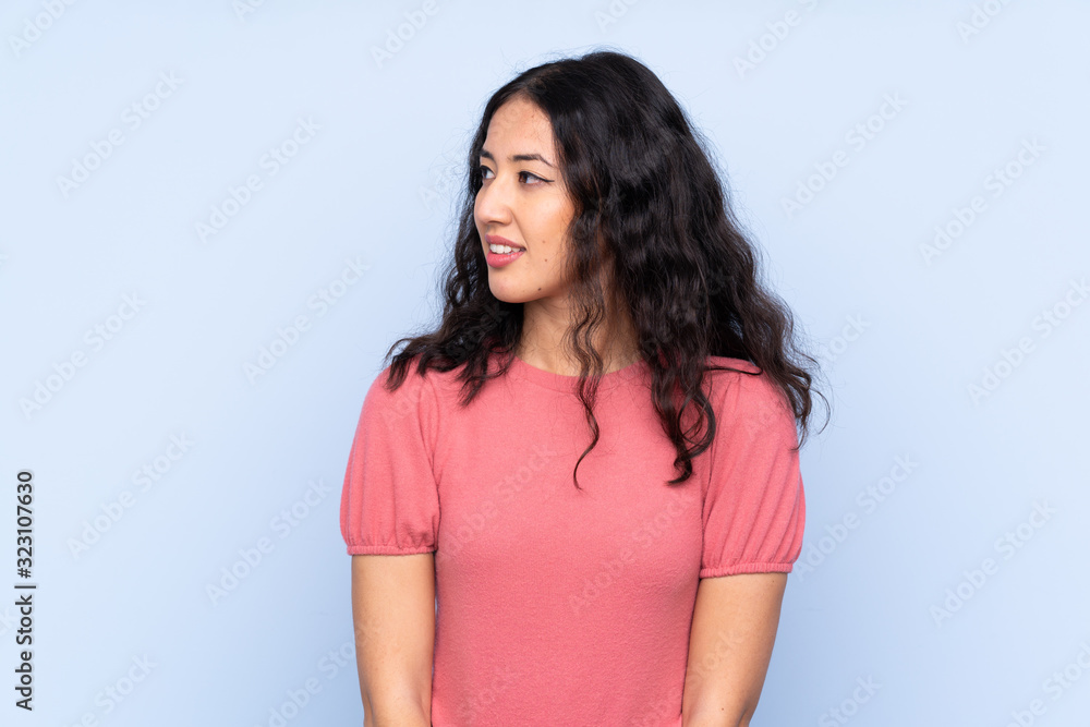 Mixed race woman wearing a sweater over isolated blue background looking to the side Mixed race woman wearing a sweater over isolated blue background looking to the side