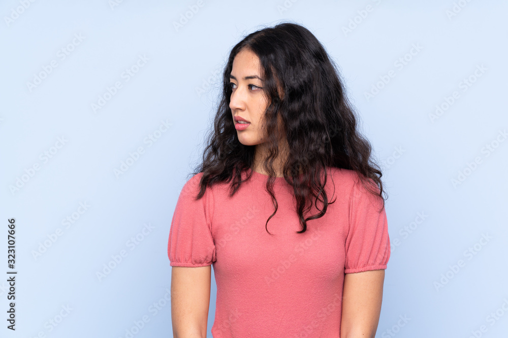 Mixed race woman wearing a sweater over isolated blue background looking side Mixed race woman wearing a sweater over isolated blue background looking side