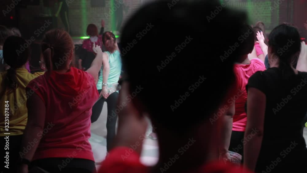 A large group of people are engaged in fitness with free entrance to the night club, play sports with music and concert lighting A large group of people are engaged in fitness with free entrance to the night club, play sports with music and concert lighting