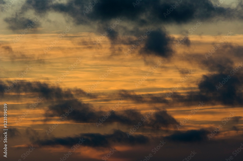 Sunset: dark clouds, and a yellow and orange sky.