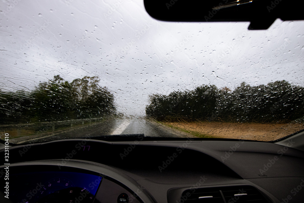 Rain falling on a windscreen while driving on a highway road without visibility