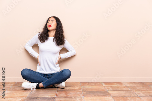 Young woman sitting on the floor suffering from backache for having made an effort