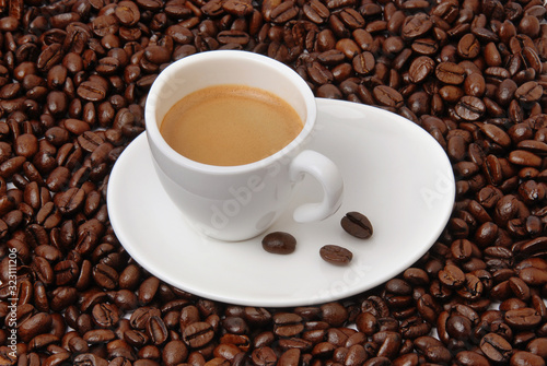 Cup of black coffee on coffee beans background. Hot aromatic americano or espresso cup on saucer.