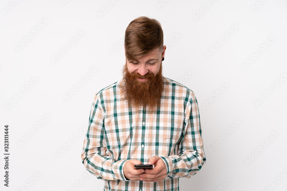 Redhead man with long beard over isolated white background sending a message with the mobile Redhead man with long beard over isolated white background sending a message with the mobile