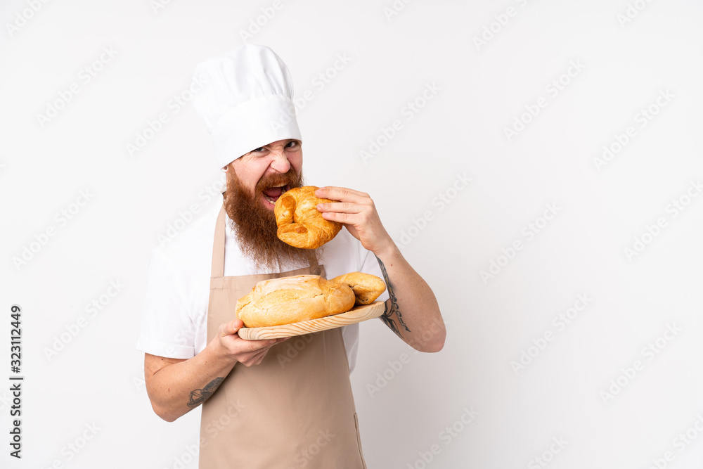 Redhead man in chef uniform. Male baker holding a table with several breads Redhead man in chef uniform. Male baker holding a table with several breads