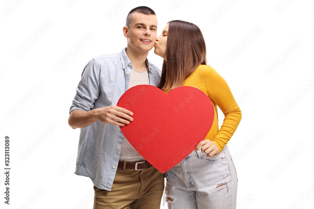 Young female kissing a guy holding a big red heart