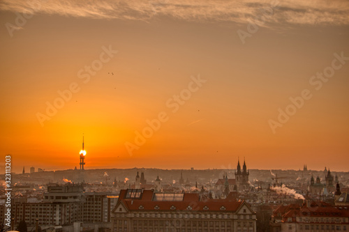 prague tv tower at sunrise wirh roofs and birds flying