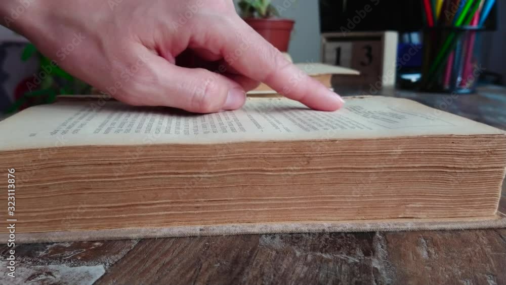 hand leafs through pages of an old book, soft focus background hand leafs through pages of an old book, soft focus background