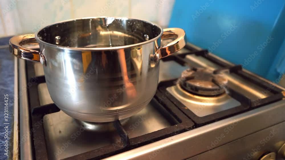 The man turns on the gas stove. The flame under the metal pan lights up The man turns on the gas stove. The flame under the metal pan lights up