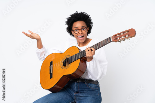 African american woman with guitar over isolated background with shocked facial expression