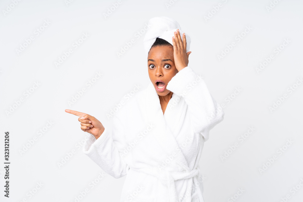 African american woman in a bathrobe over isolated background surprised and pointing finger to the side African american woman in a bathrobe over isolated background surprised and pointing finger to the side