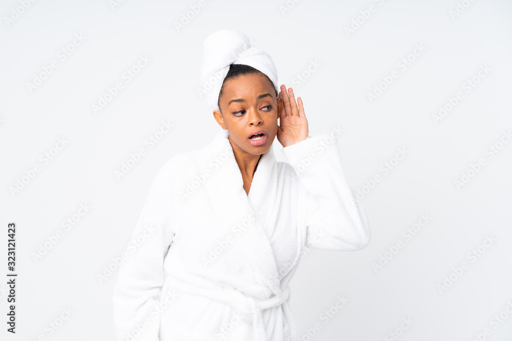 African american woman in a bathrobe over isolated background listening something African american woman in a bathrobe over isolated background listening something