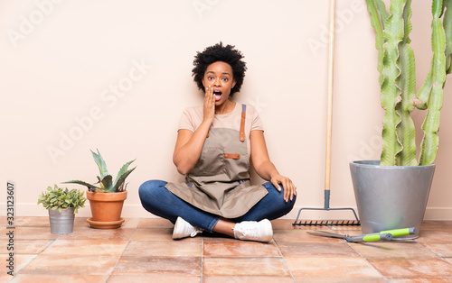 Gardener woman sitting on the floor with surprise and shocked facial expression
