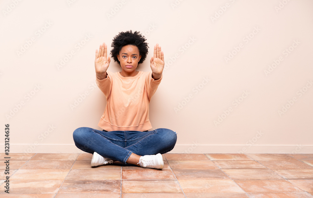 African american woman sitting on the floor making stop gesture and disappointed African american woman sitting on the floor making stop gesture and disappointed