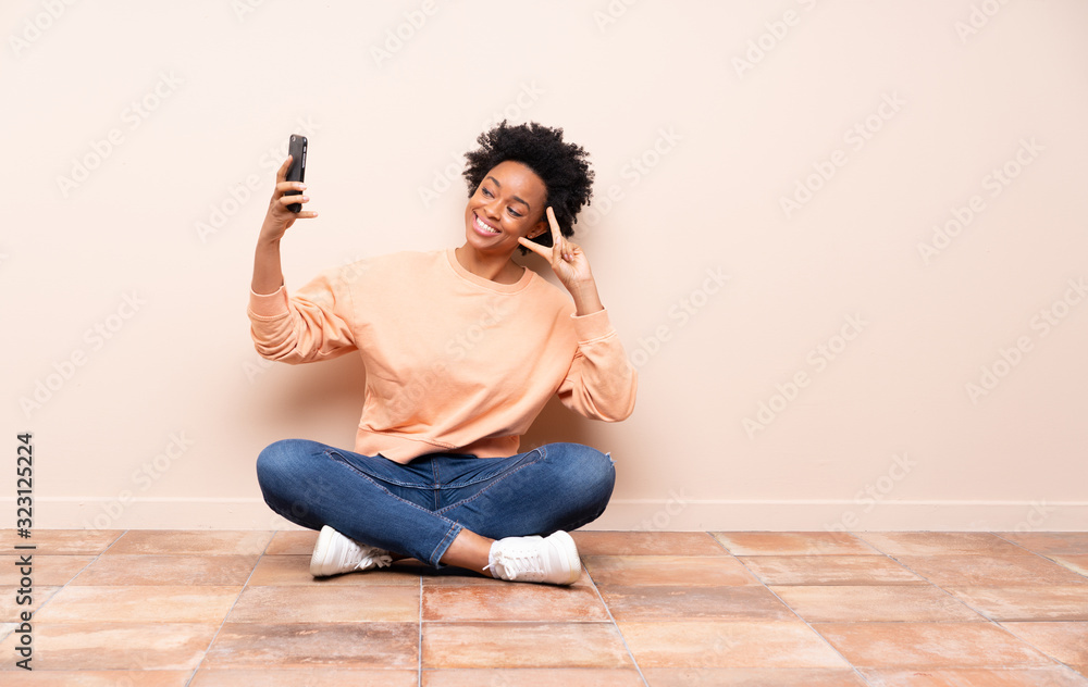 African american woman sitting on the floor making a selfie African american woman sitting on the floor making a selfie
