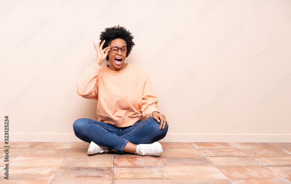 African american woman sitting on the floor with glasses and surprised African american woman sitting on the floor with glasses and surprised