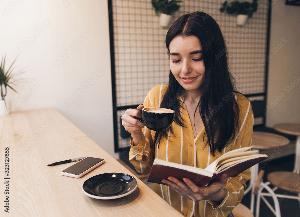 Obraz premium Pretty woman in urban cafe read book and drink black coffee