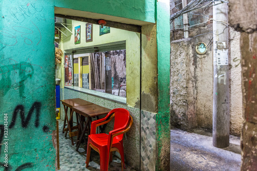 Narrow passageway with a table and chairs in the streets of Rocinha favela, a shantytown or slum in the South Zone of Rio in Brazil, South America photo