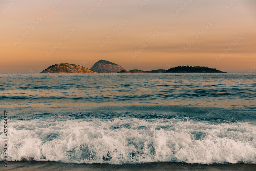View across the South Atlantic Ocean of the Natural Monument Archipelago Cagarras Islands (Ilhas Cagarras) at sunset from the seashore of Ipanema beach in Rio de Janeiro, Brazil, South America