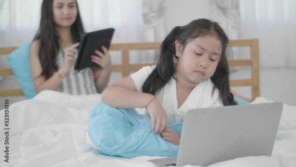 Asian girls and sisters are using laptops, computers and tablets to connect to the cyber world. The little girl rested at home using the internet. Asian girls and sisters are using laptops, computers and tablets to connect to the cyber world. The little girl rested at home using the internet.