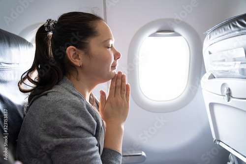 Young Woman Praying In Airplane photo
