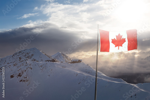 Kicking Horse, Golden, British Columbia, Canada. Beautiful Aerial View of Canadian Mountain Landscape during a vibrant sunny and cloudy morning sunrise in winter. With Flag composite